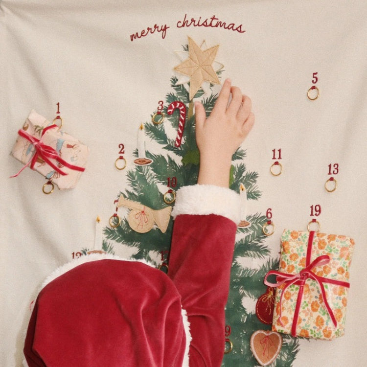 Konges Slojd Christmas Dress Red Dahlia worn by child reaching up to place a star on a festive advent calendar tree.