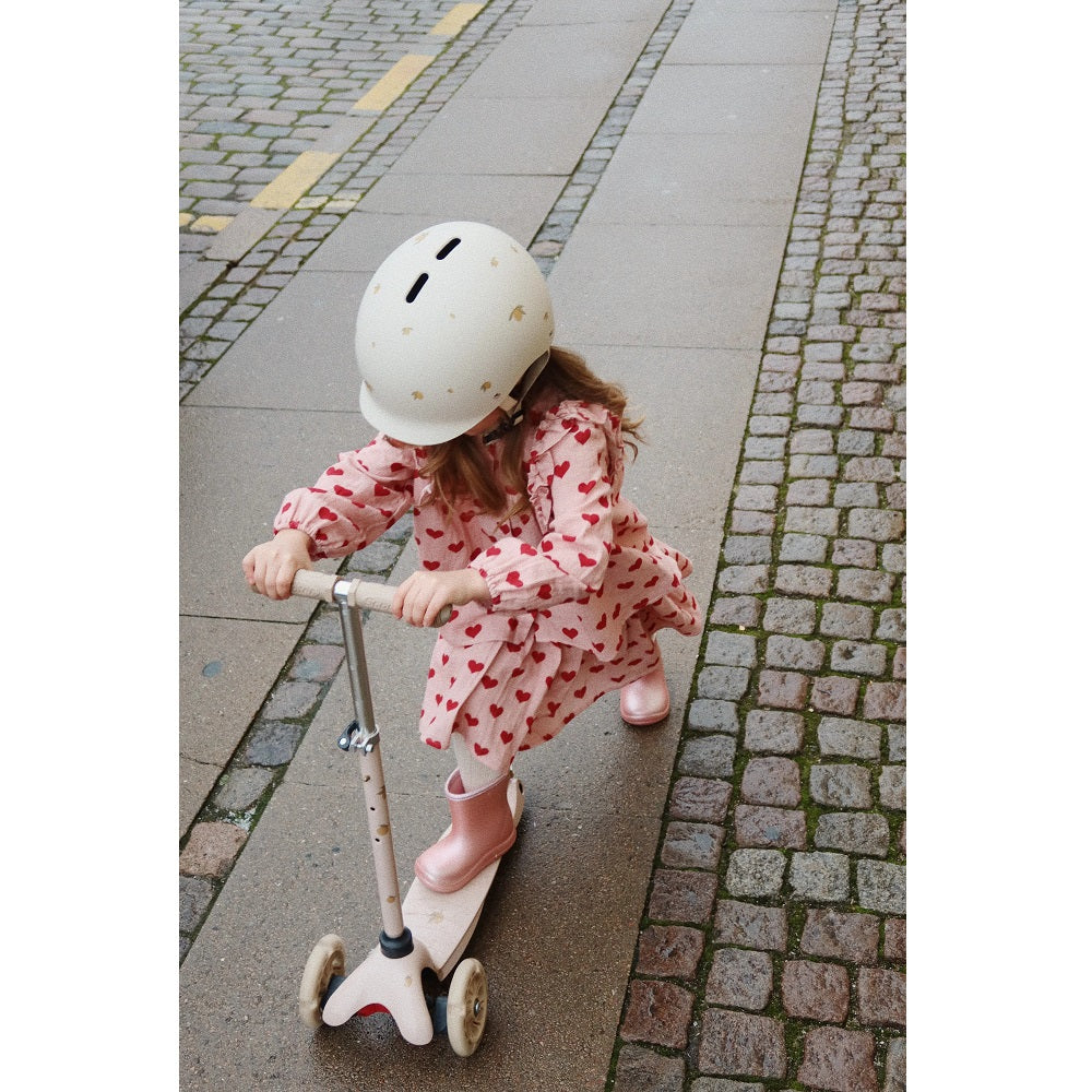 Konges Slojd Coco Skirt GOTS Amour Mellow, pink heart-print baby skirt, worn by child riding a scooter.