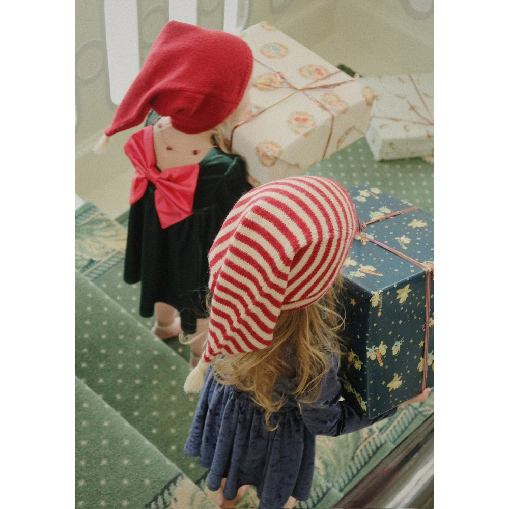 Konges Slojd Gia Bow Dress Pine Grove, navy toddler dress with pink bow, as a child carries a festive gift box.