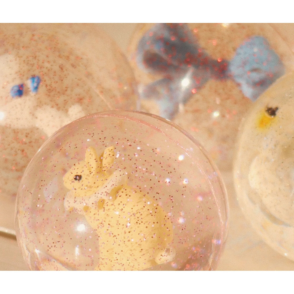 Konges Slojd Glitter Bouncing Ball Set Poodle/Bow; pink glitter globe encloses a yellow poodle toy.