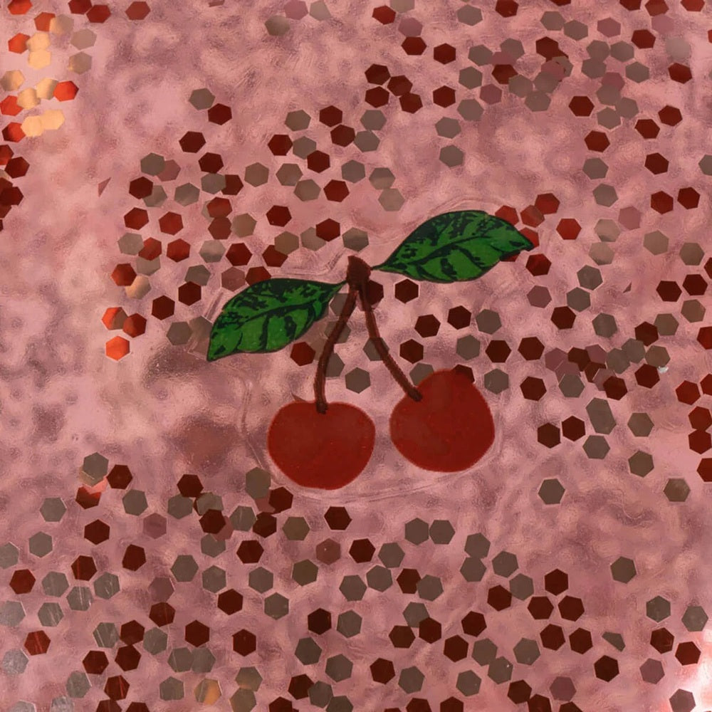 Konges Slojd Glitter Glitter Jump Ball Cherry on a pink glittery surface with red cherries and green leaves
