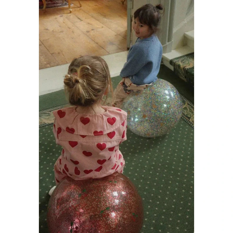 Konges Slojd Glitter Glitter Jump Ball Lemon; children sit astride glittery bounce balls in pink and blue.