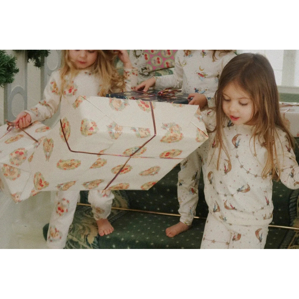 Konges Slojd Holiday Basic Blouse/Pants Set GOTS Luna worn by kids in cream prints as they lift a large wrapped gift.