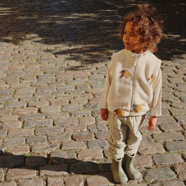Konges Slojd Jody Teddy Vest Mon Grand Citron for toddlers; beige teddy fleece with pom pom accents
