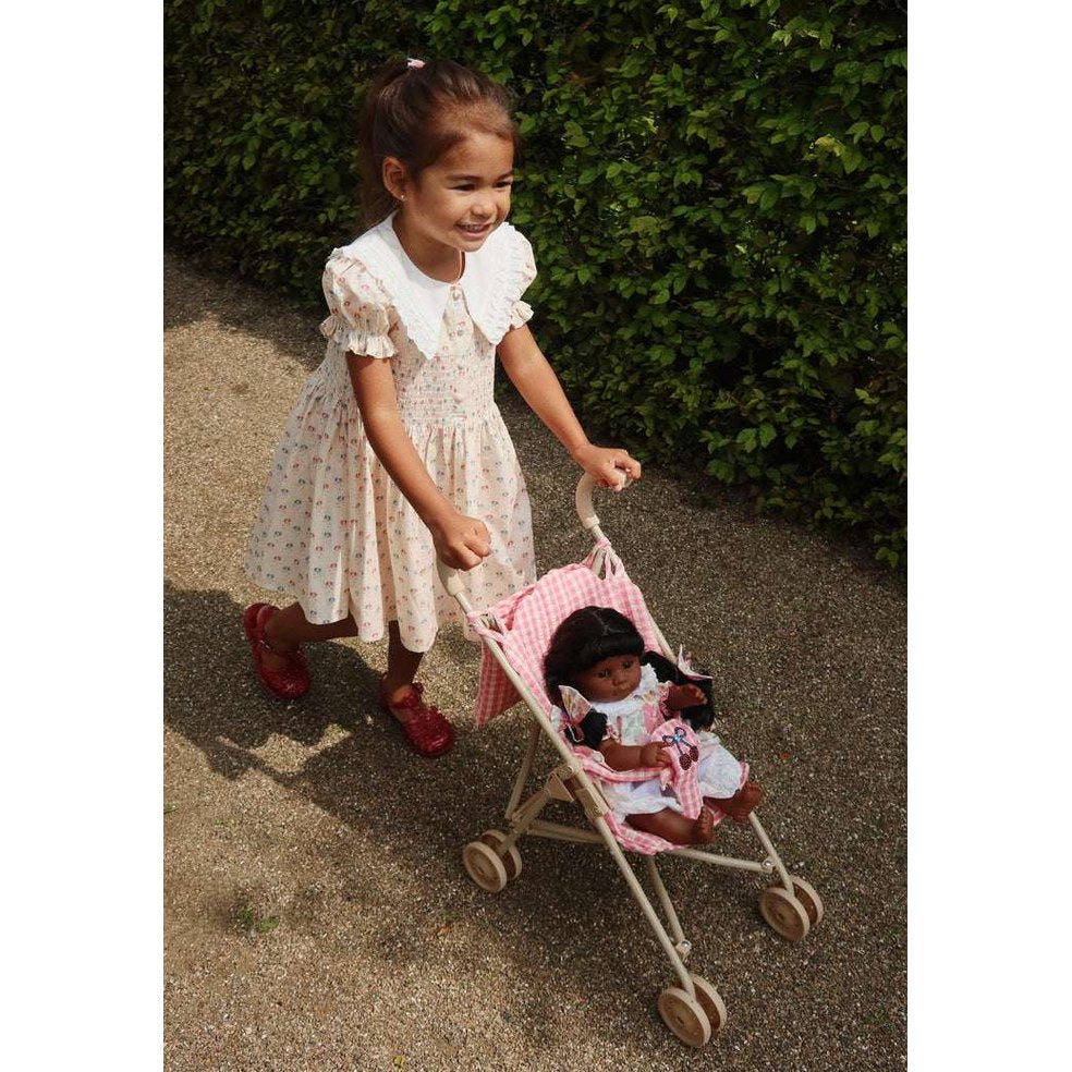 Konges Slojd Midsummer Dress GOTS Pipa Petite; white floral dress with large collar, girl pushes pink gingham doll stroller