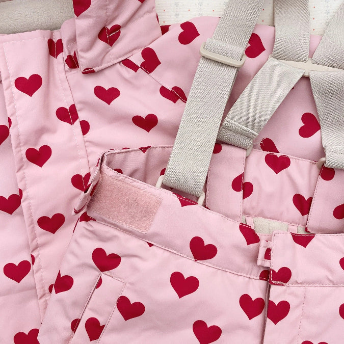 Konges Slojd Mismou Jacket Amour Pink with red hearts; adjustable gray shoulder straps shown on baby outerwear.