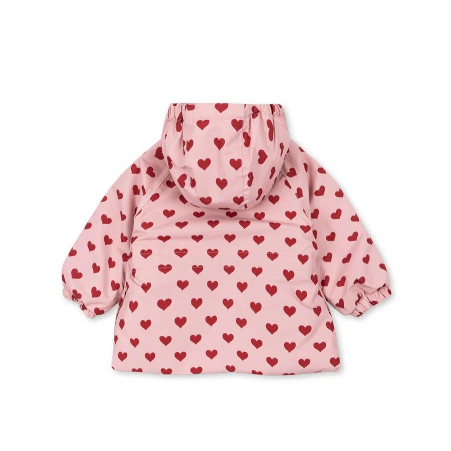 Konges Slojd Mismou Jacket Amour Pink, pink hooded baby jacket with red hearts, laid flat to show print and puff sleeves.