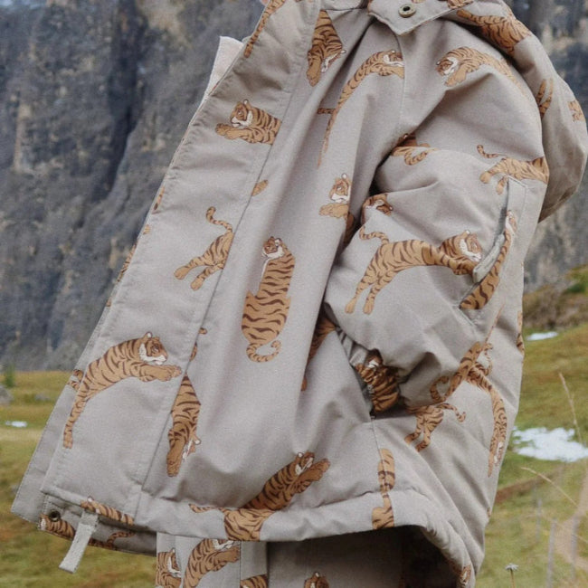 Konges Slojd Mismou Jacket Tiger Oak worn by a toddler outdoors in a beige tiger-print coat.