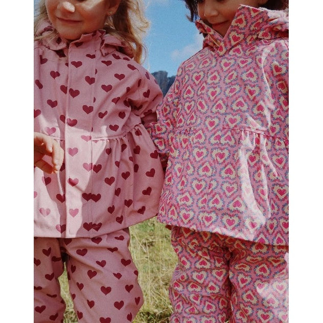 Konges Slojd Rainy Palme Set Amour Pink rain suits for toddlers; pink heart pattern, two kids wearing matching outfits