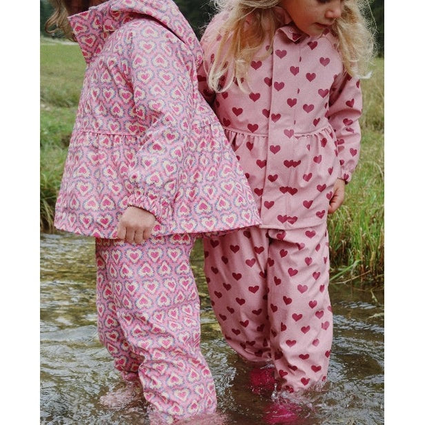 Konges Slojd Rainy Palme Set Amour Pink; toddler pink heart-print rain outfits, two children in water.