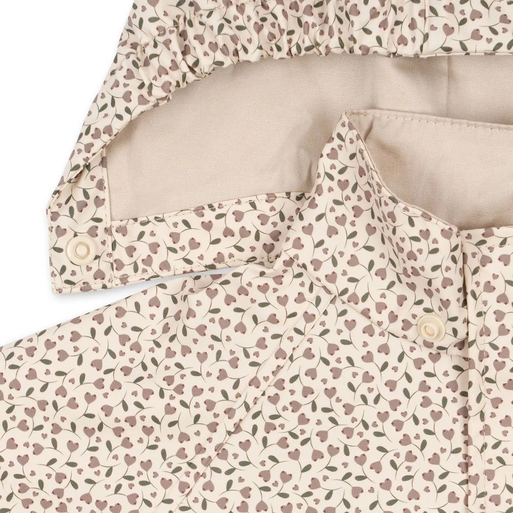 Konges Slojd Rainy Palme Set Milk Tank baby raincoat in cream floral pattern, front buttons visible.