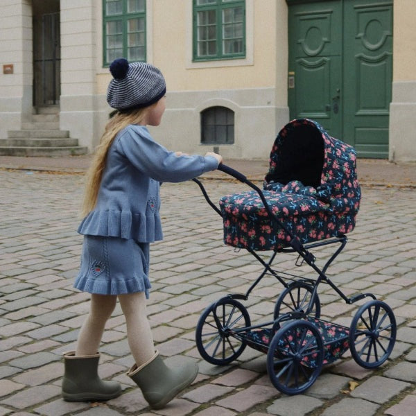 Konges Slojd Soleil Cardigan in Country Blue worn by a child pushing a floral baby pram