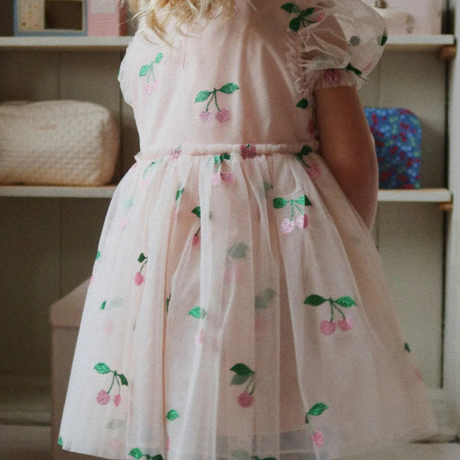 Konges Slojd Tullie Dress Pink Glitter; a child twirls in pink cherry-print tulle with puff sleeves.