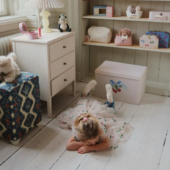 Konges Slojd Tullie Dress Pink Glitter: child lying on a white floor in a pastel room, flaunting the glittery tutu.
