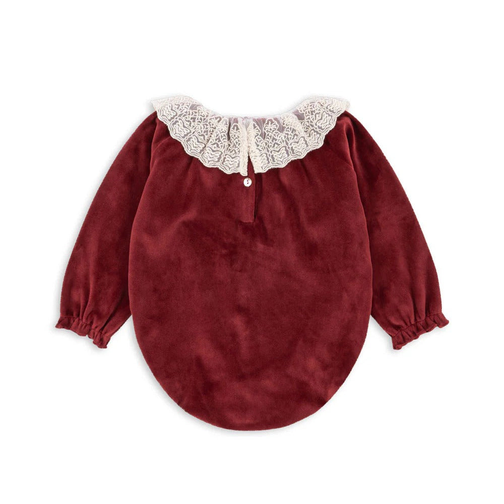 Konges Slojd Venola Romper Red Dahlia, velvet baby romper with ivory lace collar and elastic cuffs shown flat.