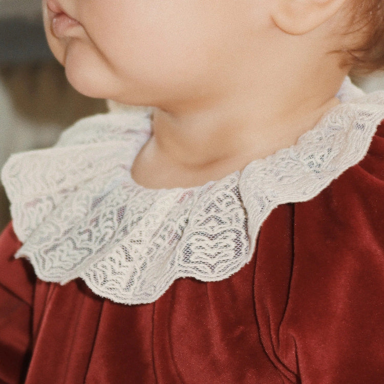Konges Slojd Venola Romper Red Dahlia featuring white lace collar worn by a baby in velvet red fabric.