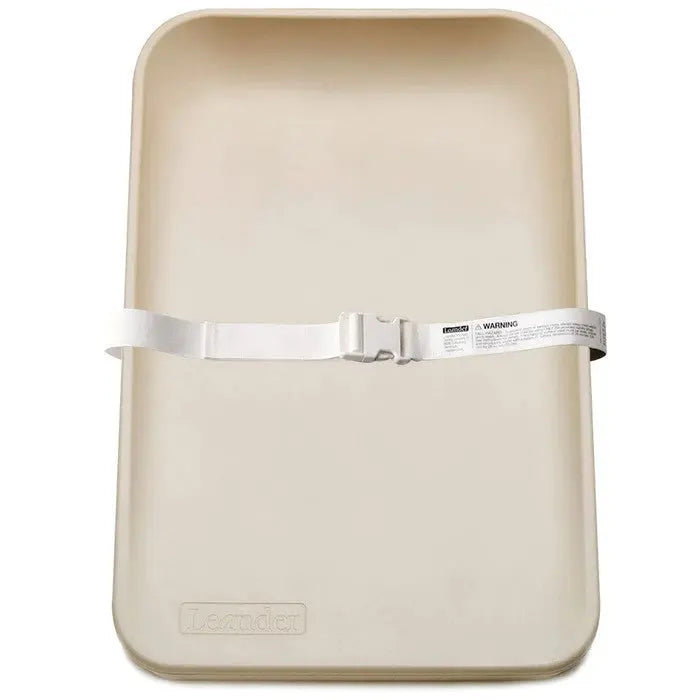 Leander Matty Changer changing mat in beige with a white safety strap secured across the center.