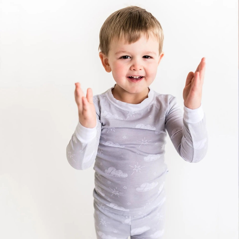 Little Sleepies Bamboo Pajama Set Clouds, toddler in grey cloud-print PJs clapping hands.