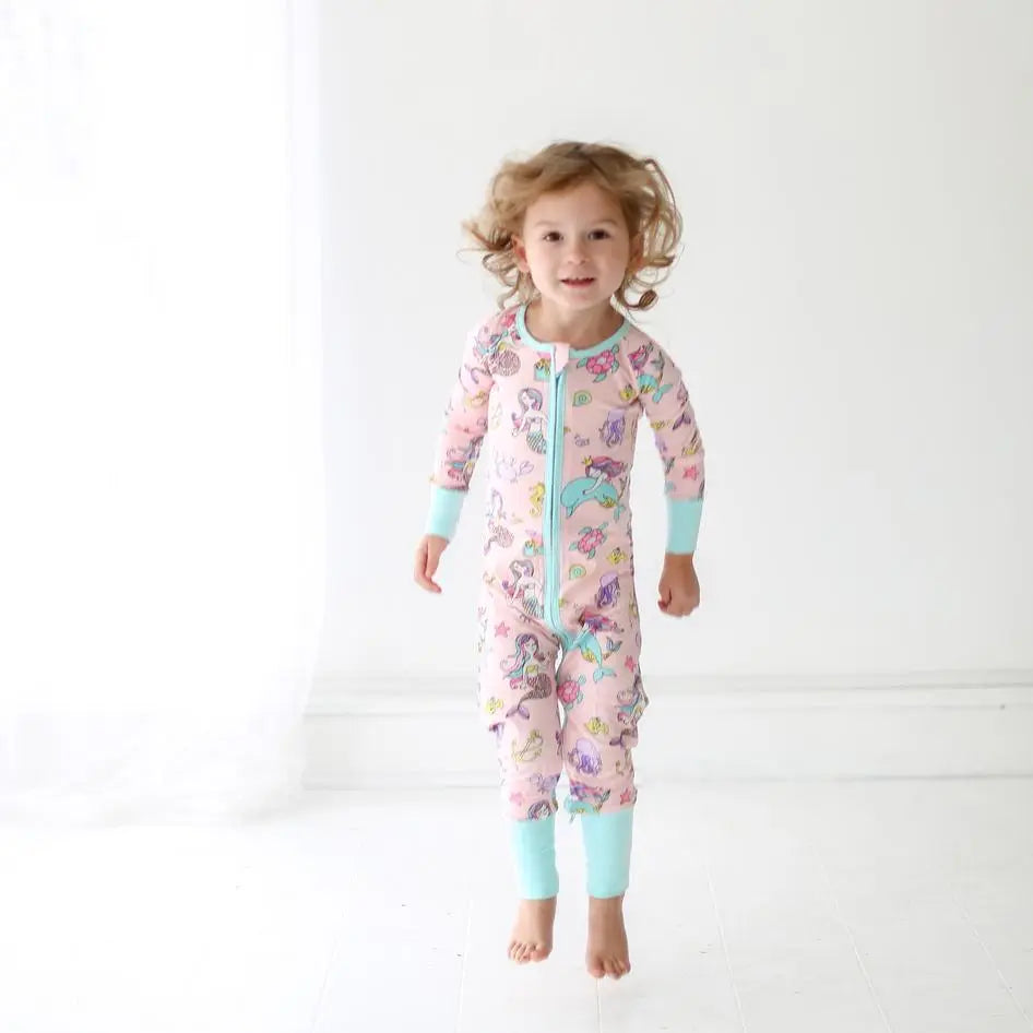 Little Sleepies Bamboo Zip Romper/Sleeper Mermaid, pink with turquoise cuffs, toddler mid-jump showing mermaid print.