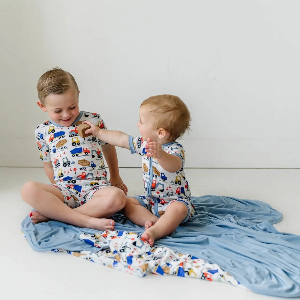 Littlesleepies Construction Two Piece Short Sleeve & Shorts Bamboo Viscose Pajama Set, two siblings in matching print playing on a blue blanket.