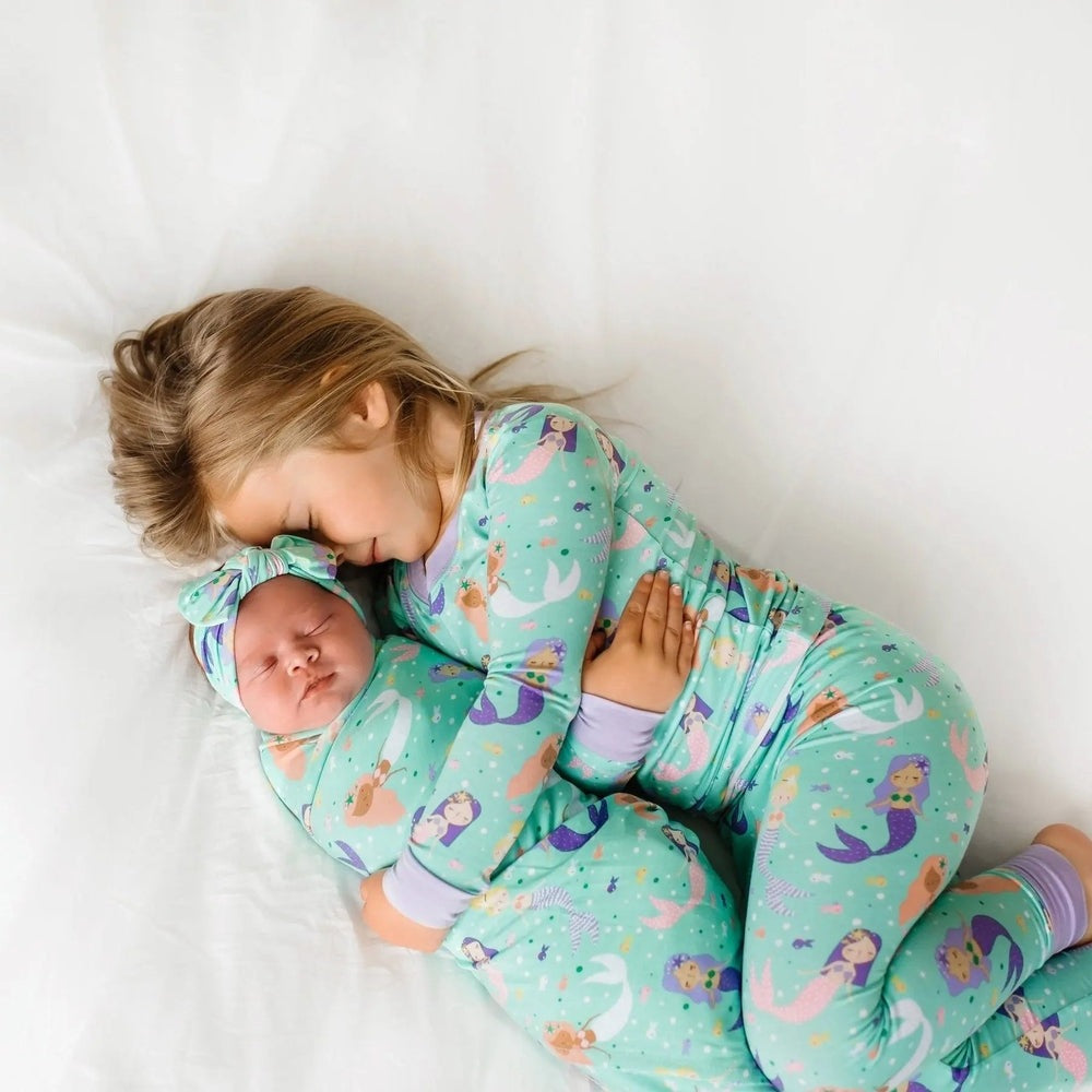 LITTLESLEEPIES Mermaid Magic Two Piece Bamboo Viscose Pajama Set; siblings cuddle in teal mermaid-print PJs, proving soft, cozy bedtime wear.