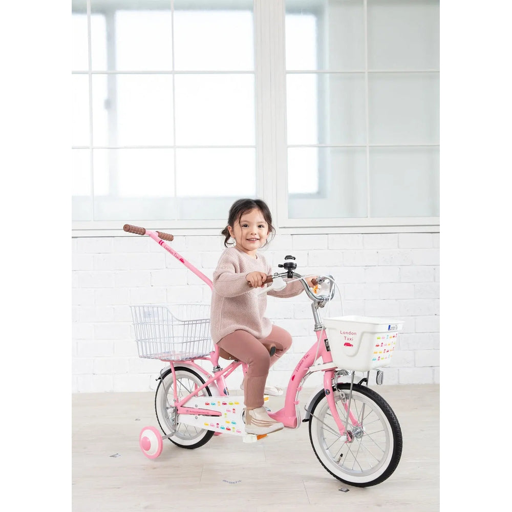 London Taxi 14-Inch Kids Bike with Pushbar in pink, front basket, girl rider smiling on indoors ride.