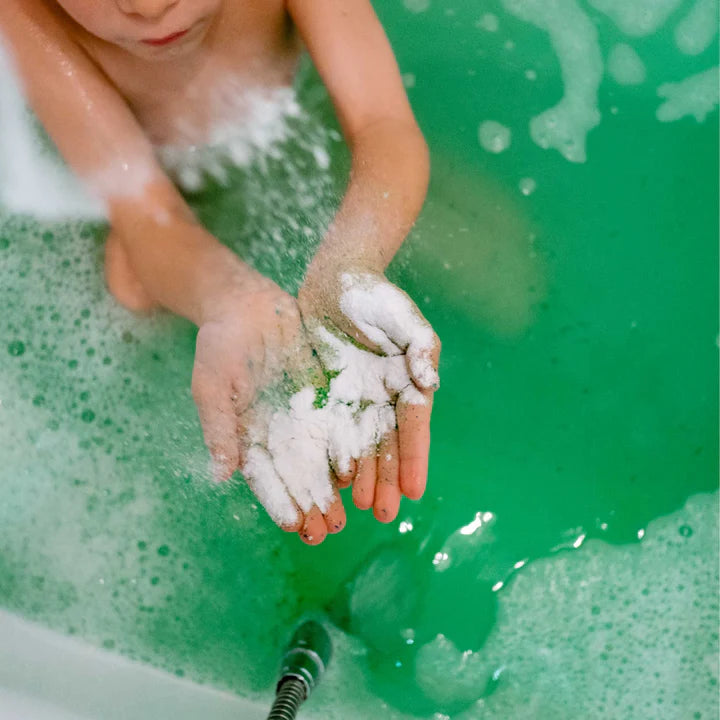 Loot Toy Co foaming bath powder lime held by a child over green bathwater