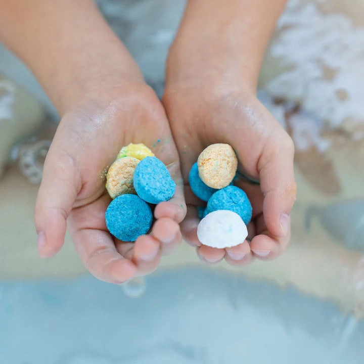 Loot Toy Co Funky Fish Food Hullabaloo Blue bath fizzies held in hands; blue, white and yellow tablets