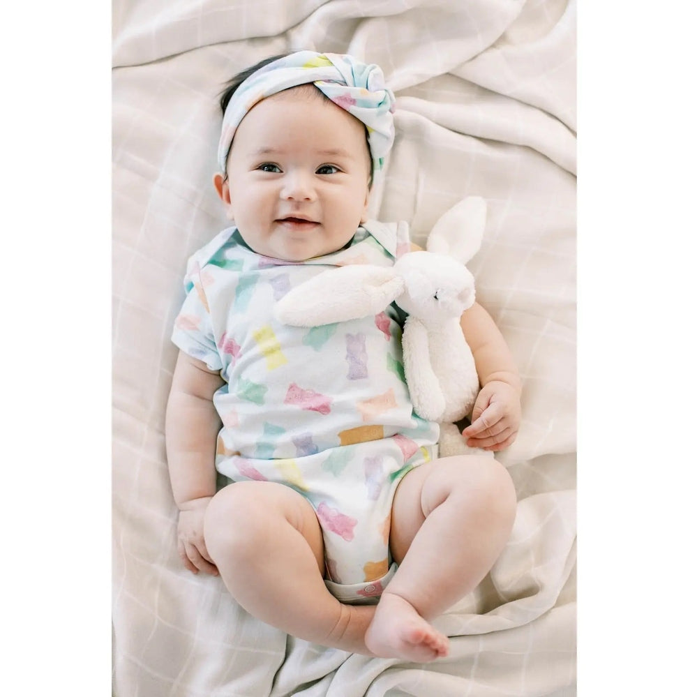 Loulou Lollipop Baby Bodysuit Gummy Bears in pastel print; smiling baby sits with a plush bunny.