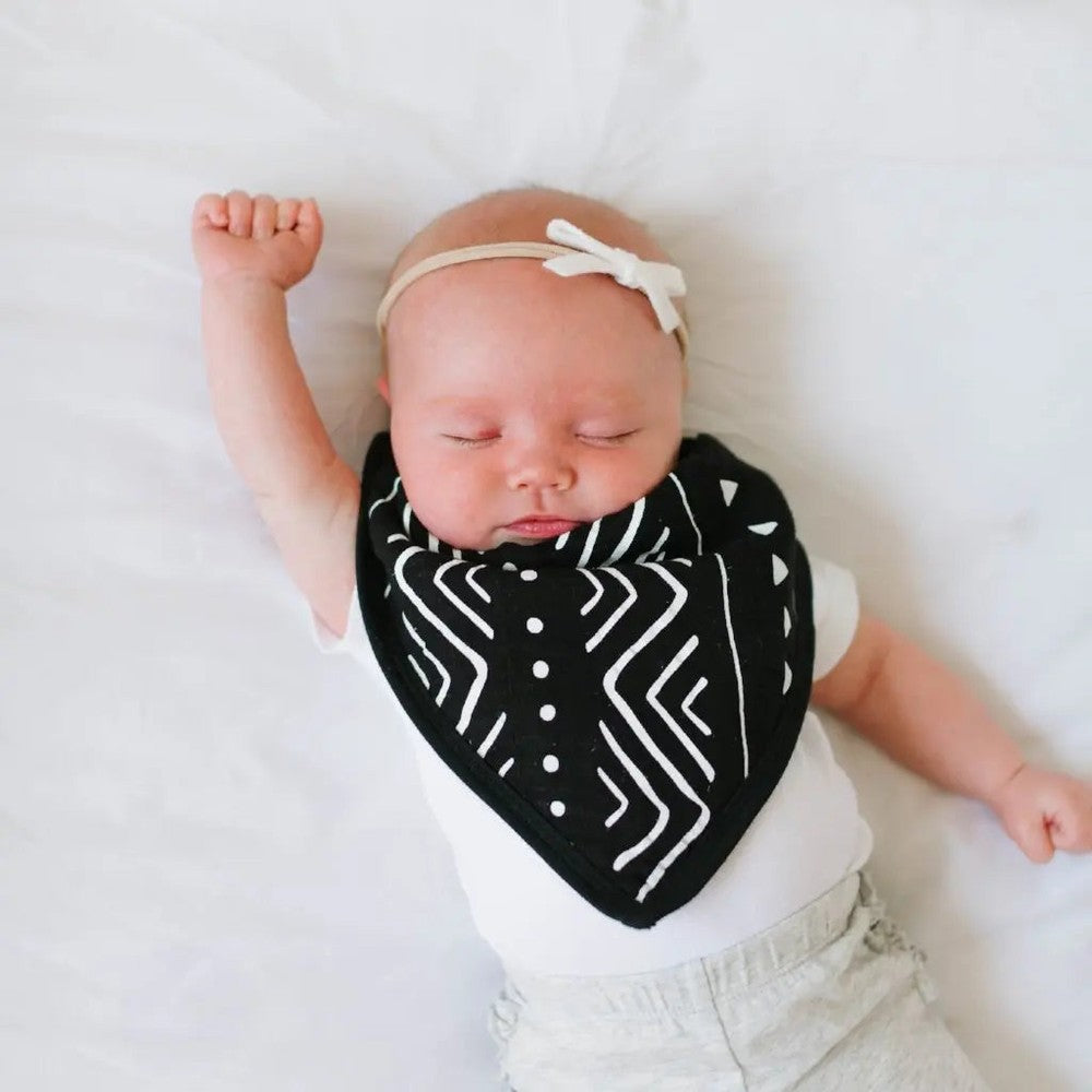 Loulou Lollipop Bandana Bib Set on a peacefully sleeping baby, black geometric bib tied at the neck with a beige headband.