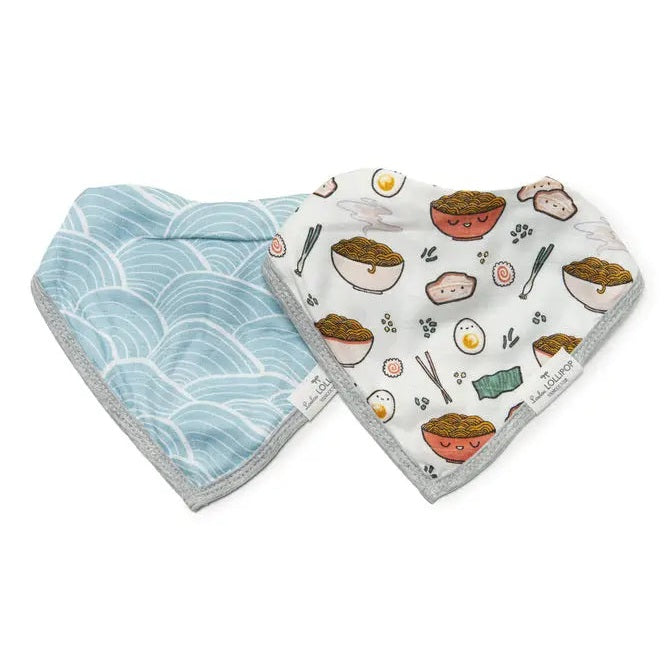 Loulou Lollipop Bandana Bib Set with blue wave-print and food-print bibs, two soft gray-trim bibs laid flat for mealtime.