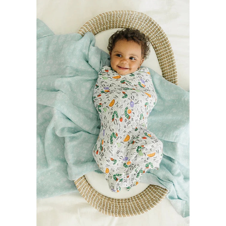 Loulou Lollipop Eric Carle Muslin Swaddle in multi-color fruit print; baby wrapped snugly in a soft blanket.