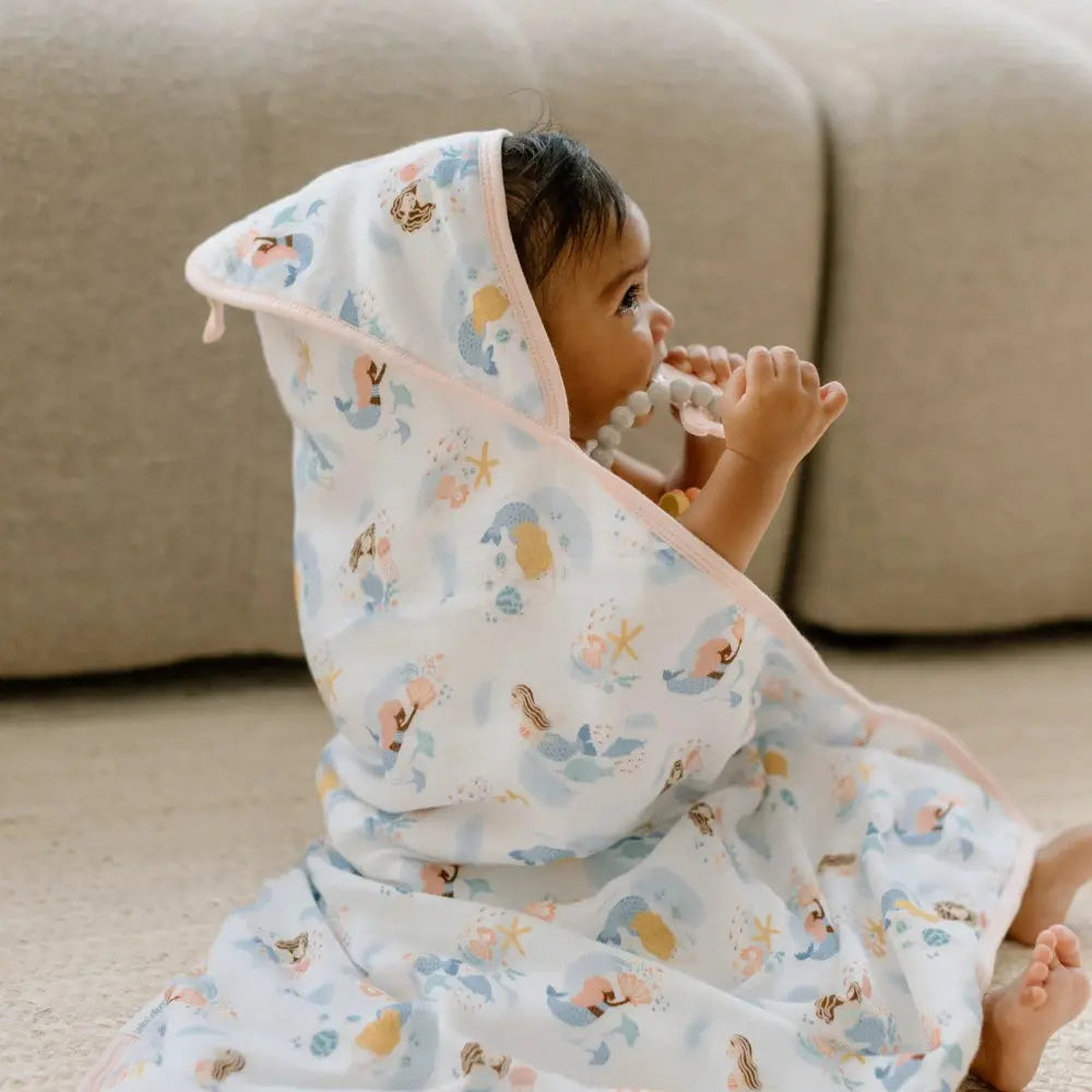 Loulou Lollipop Hooded Towel Set: baby snugly wrapped in pastel sea-print hooded towel after bath.