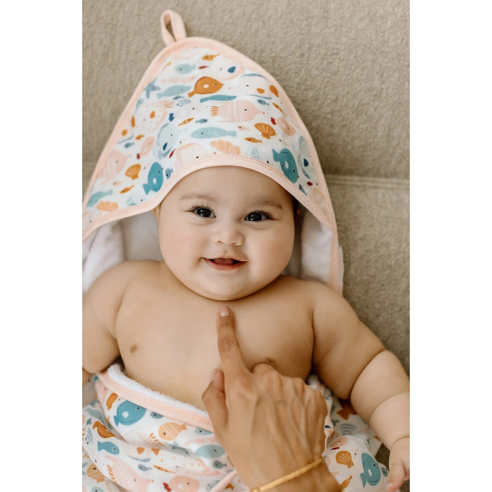 Loulou Lollipop Hooded Towel Set in pink-trim fish-print hood on smiling baby