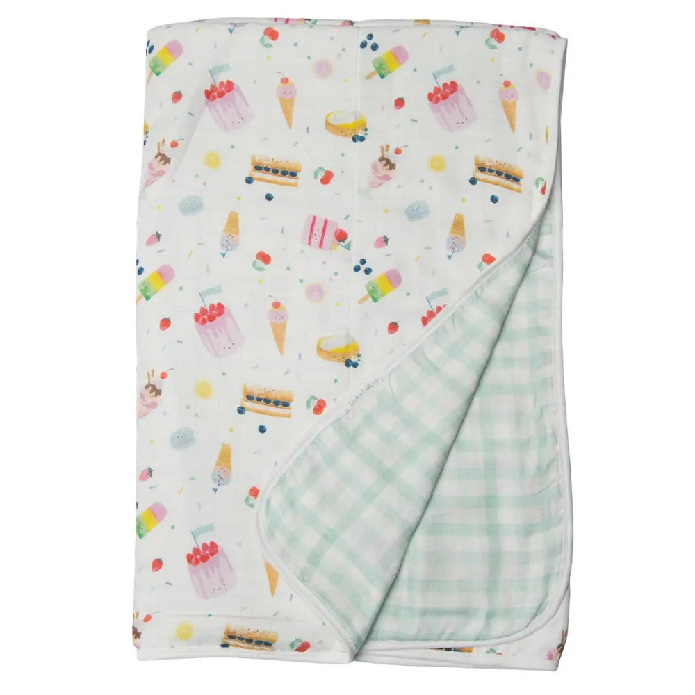Loulou Lollipop Muslin Quilt Blanket, white ice-cream print with mint gingham reverse, folded at the corner.