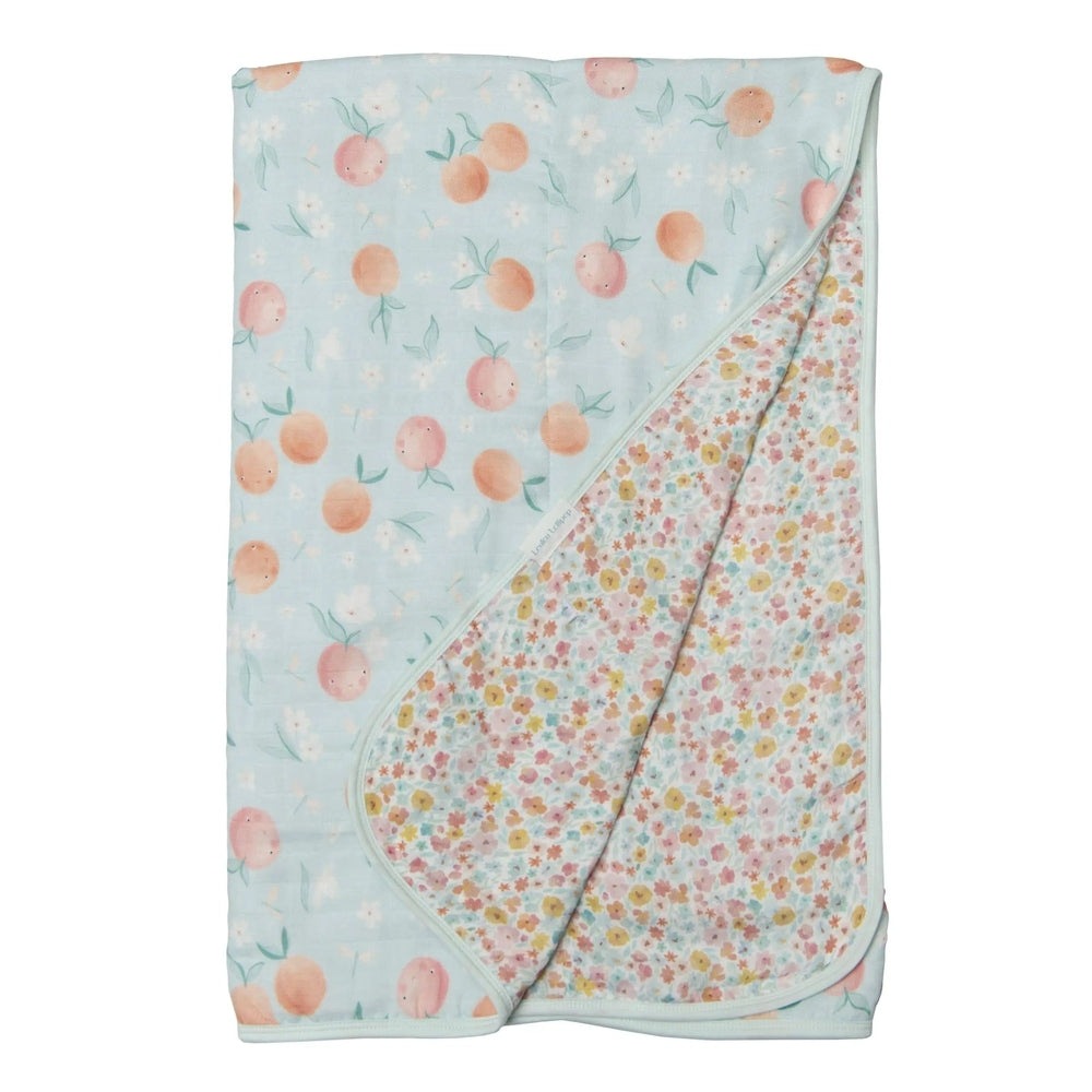 Loulou Lollipop Muslin Quilt Blanket in mint blue with peach prints, folded to reveal floral reverse for swaddling.