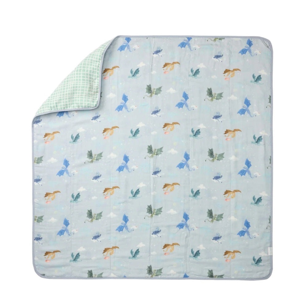 Loulou Lollipop Muslin Quilt Blanket in light blue with whimsical unicorn pattern, green checkered corner visible.