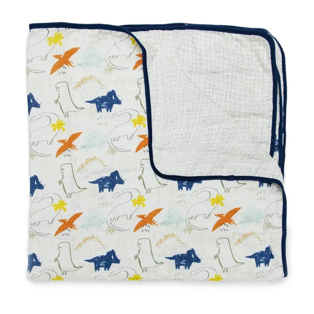 Loulou Lollipop Muslin Quilt Blanket in colorful dinosaur print with navy binding, folded to show soft muslin backing.