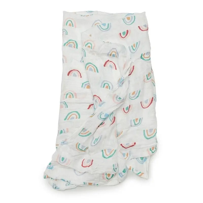 LOULOU LOLLIPOP Muslin Swaddle blanket, white with pastel rainbows, crumpled and draped to suggest swaddling comfort.
