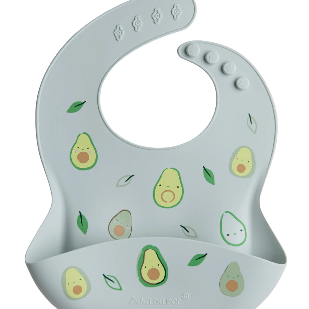 Loulou Lollipop Silicone Bib in pale blue with avocado prints; curved pocket catches spills during feeding.