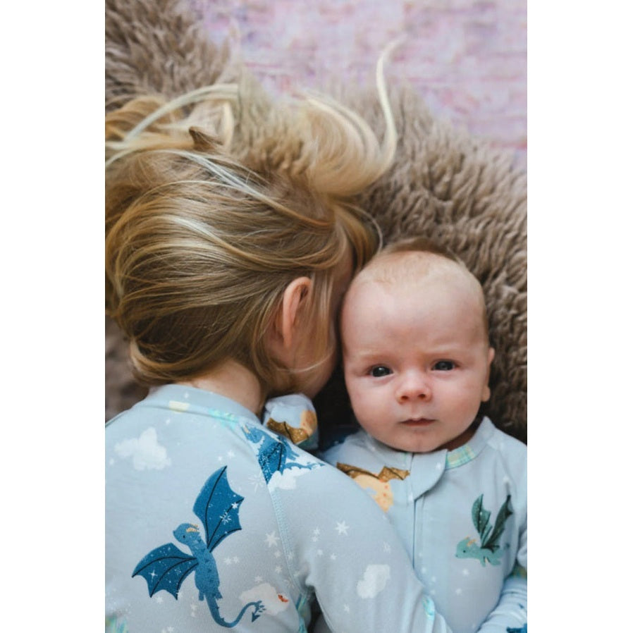 LOULOU LOLLIPOP Sleeper Magical Dragons: soft blue baby sleepwear with dragon print, as a mother cuddles her baby.