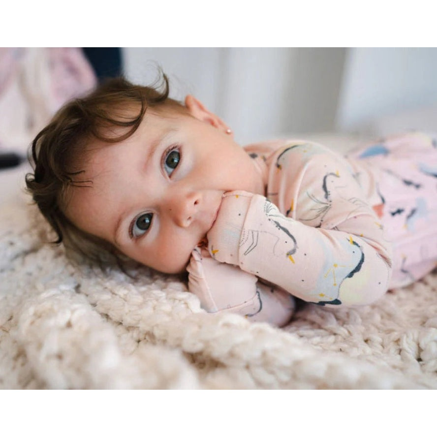 Loulou Lollipop Sleeper Unicorn Ballet: a cozy pink baby sleeper with unicorn prints, lying on a fluffy rug.
