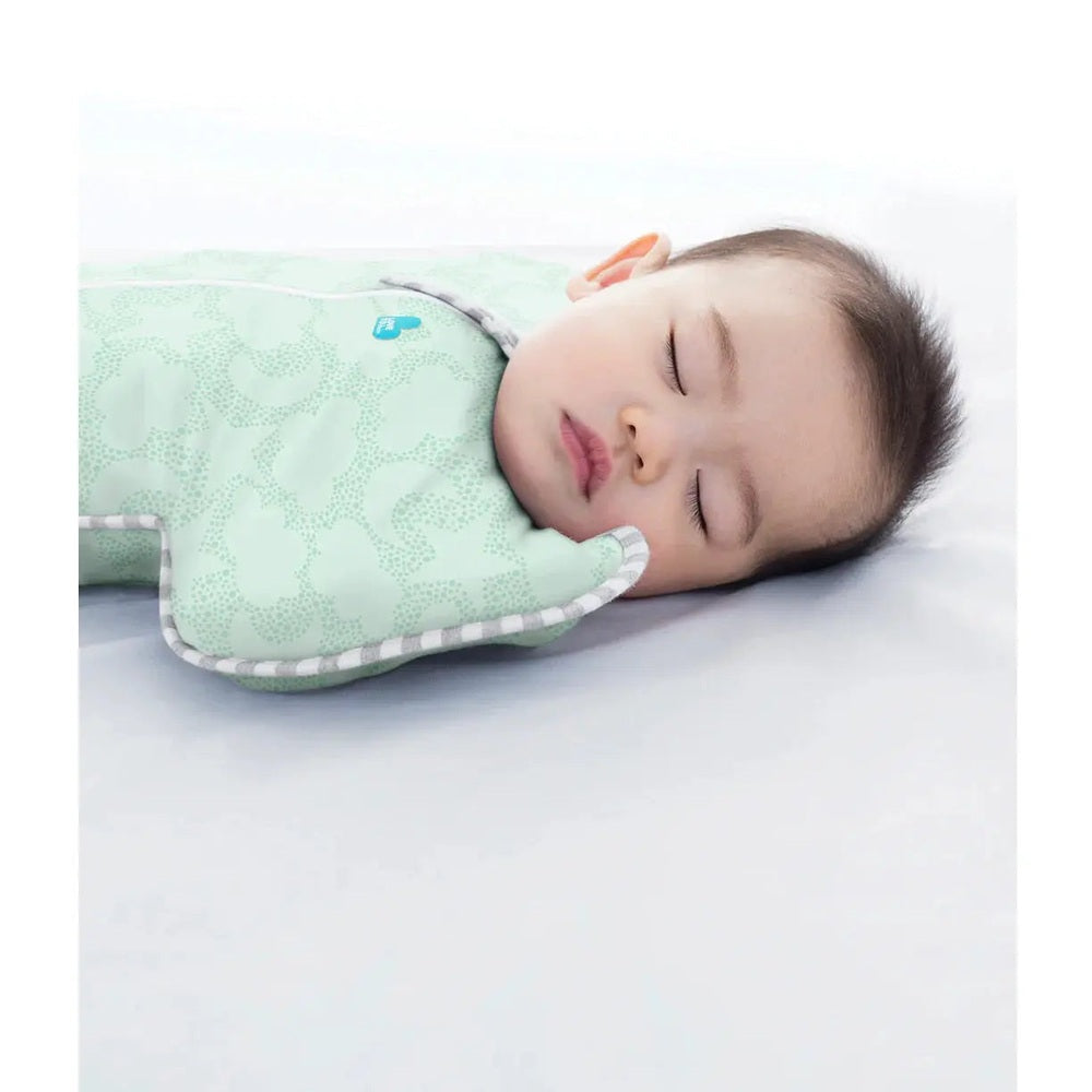 Love To Dream Swaddle Up Organic Cotton 1.0 Tog Celestial Dot Mint, baby sleeping securely in a mint swaddle with arms up.