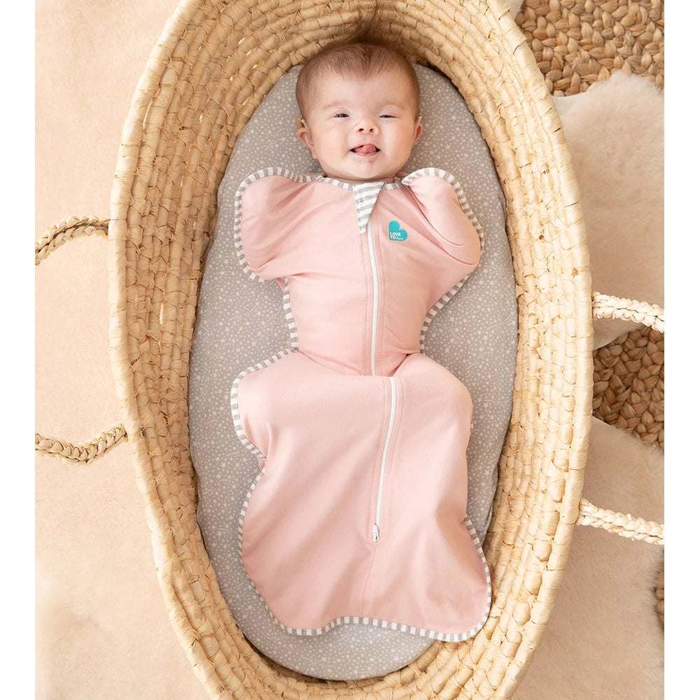 Love To Dream Swaddle Up Original Cotton 1.0 Tog Dusty Pink, baby snugly swaddled in a woven bassinet.