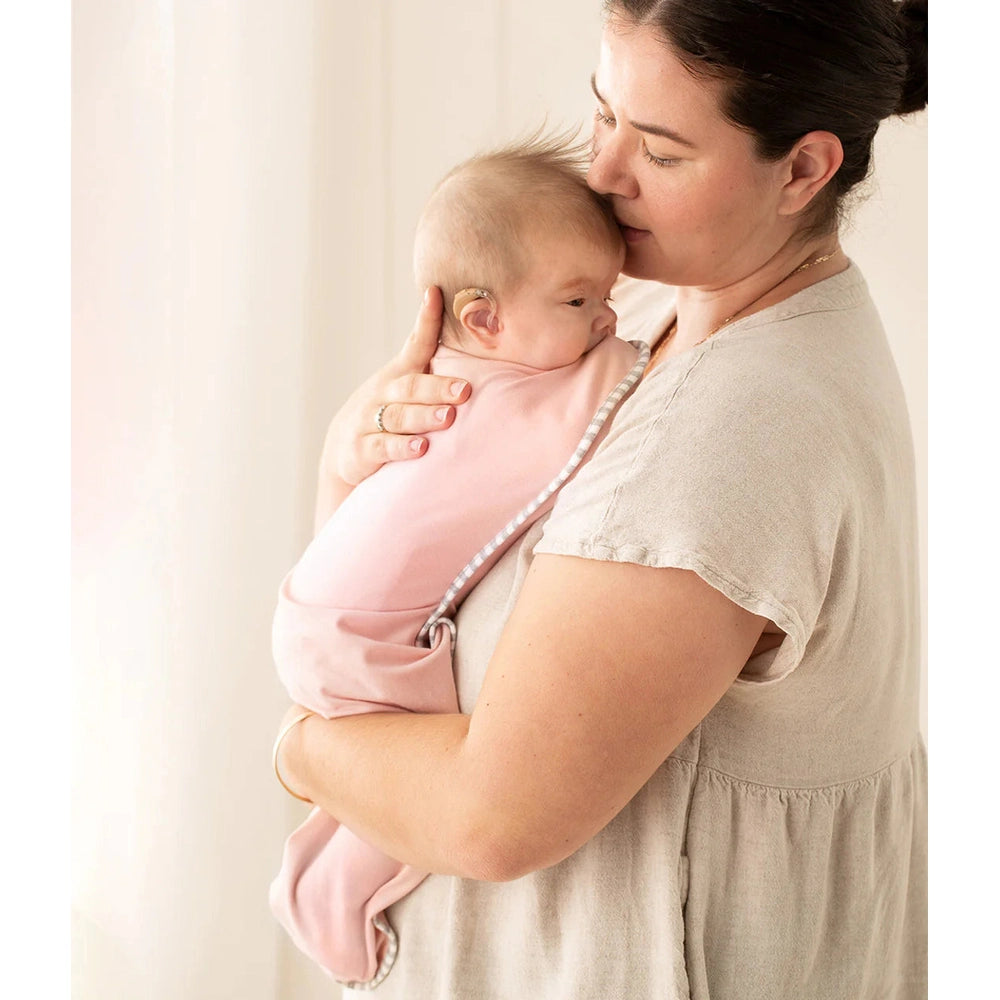 Love To Dream Swaddle Up Original Cotton 1.0 Tog Dusty Pink; baby snugly swaddled in soft pink as mom cradles.