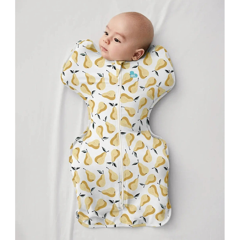 Love To Dream Swaddle Up Original Cotton 1.0 Tog pear print ochre swaddle, baby lying swaddled with visible front zipper.