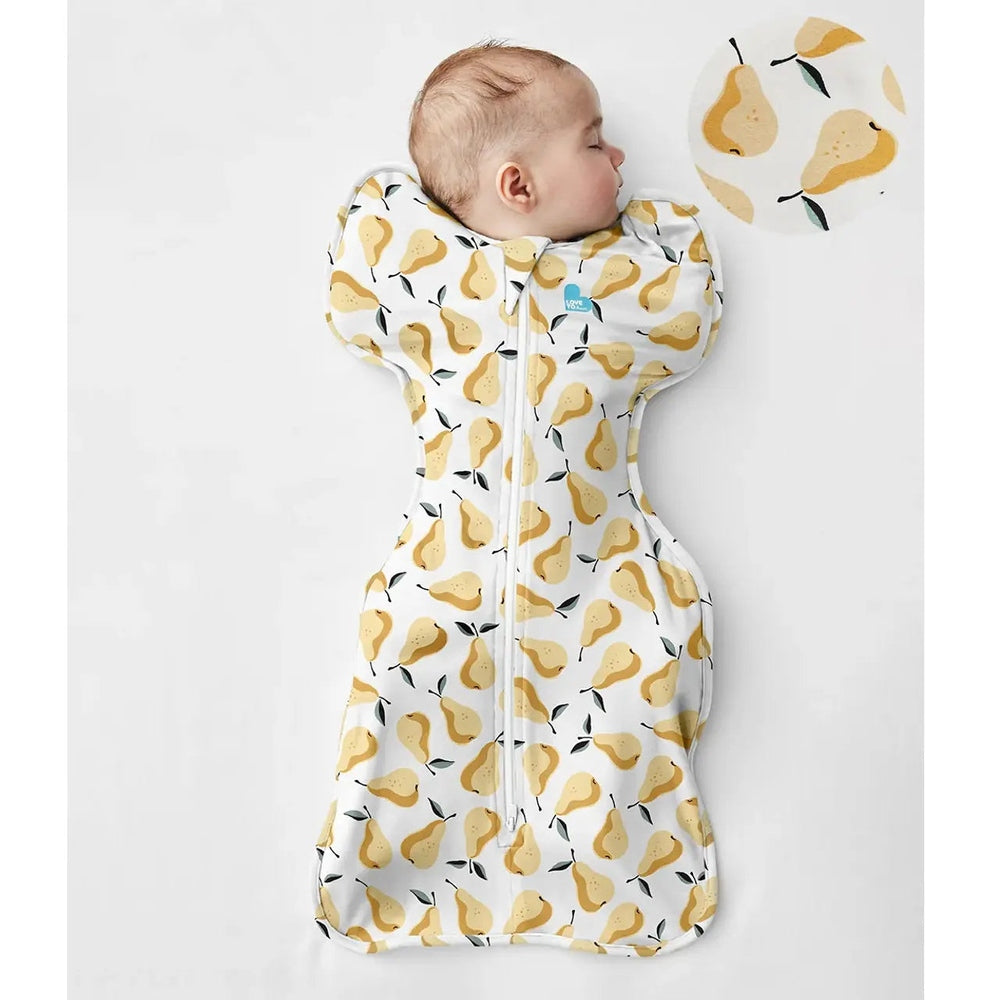 Love To Dream Swaddle Up Original Cotton 1.0 Tog Pear Print Ochre baby swaddle wrapped around sleeping infant
