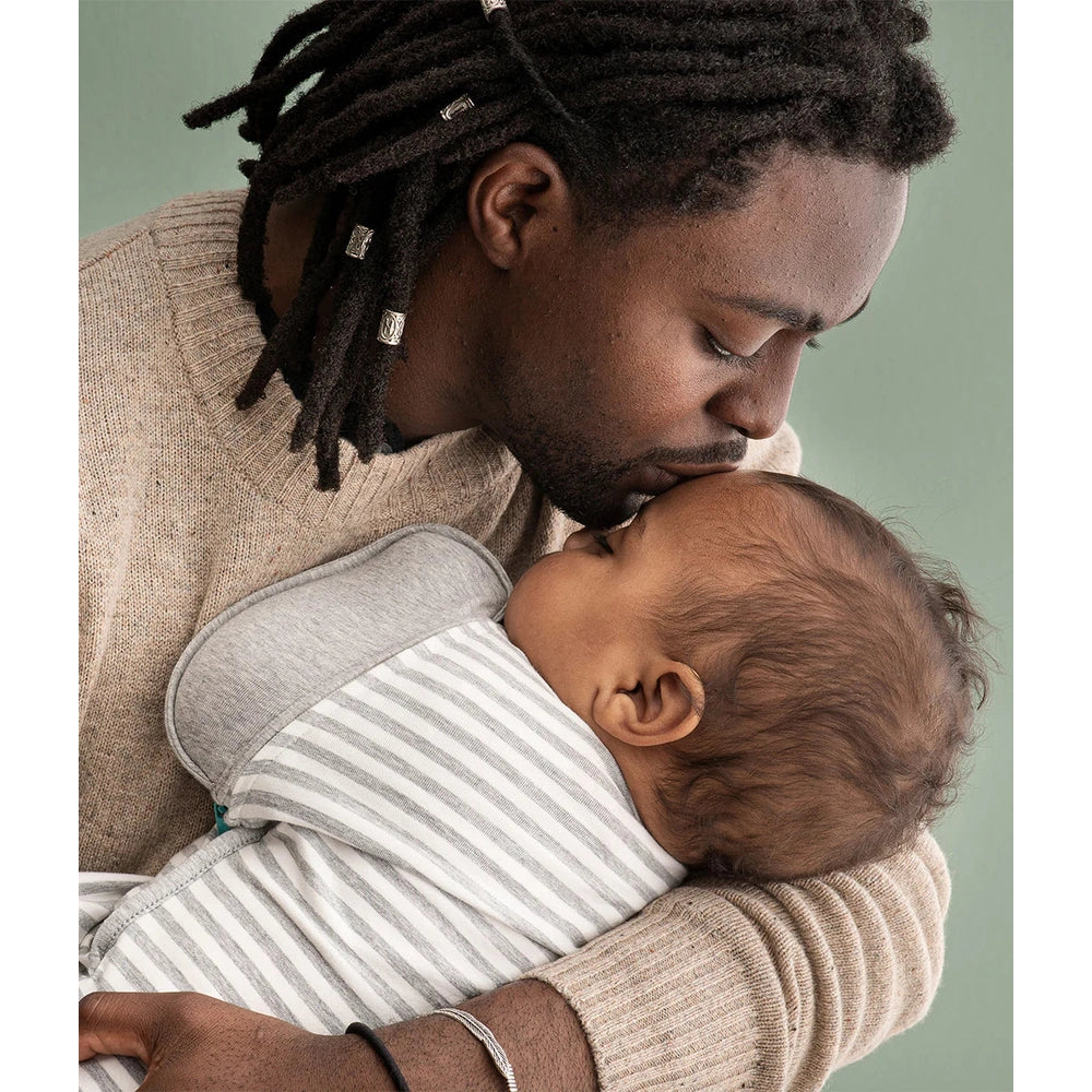 Love To Dream Swaddle Up Transition Bag Original Cotton 1.0 Tog White Dreamer, baby snug in a gray-striped cocoon in parent’s arms.