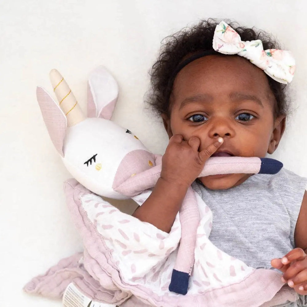 Lulujo Lovely Muslin Cotton baby blanket in soft pink, shown with a plush bunny as the baby snuggles it.
