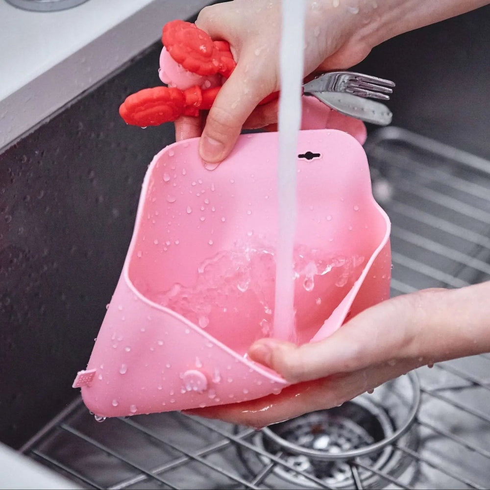 Marcus & Marcus Cutlery Pouch in pink silicone being rinsed under running water.